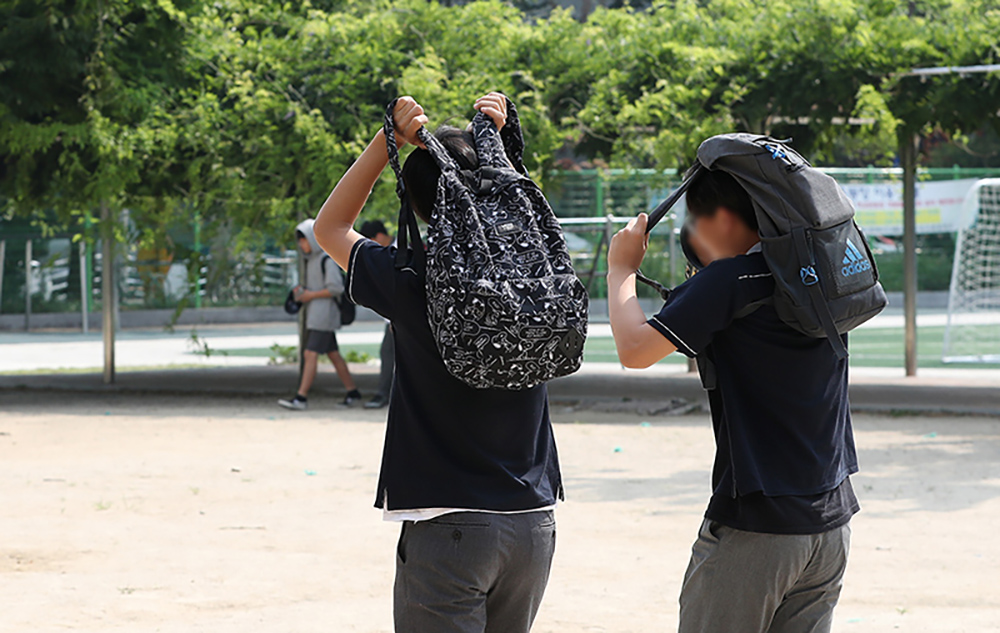 단축수업을 마친 학생들이 가방으로 태양을 피하고 있다.  [대한민국 정책브리핑]